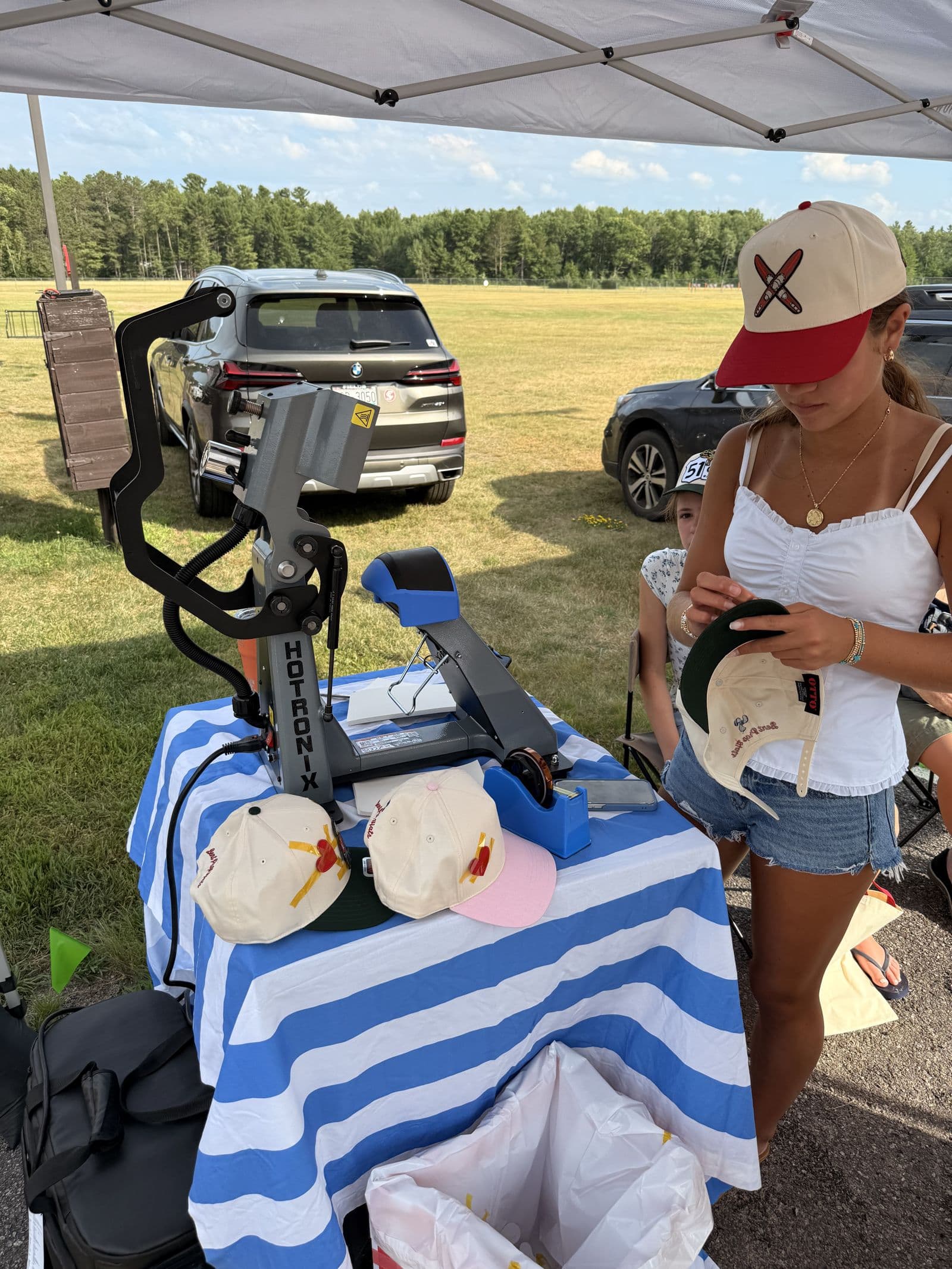 Pressing a hat at the Bent Prop tent, blanks stacked on the striped table